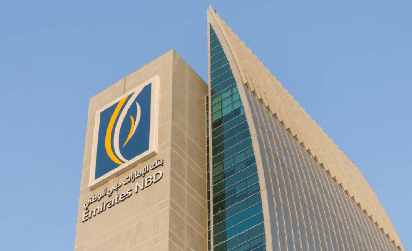 Low-angle view of the Emirates NBD headquarters featuring its logo and sharp glass facade.